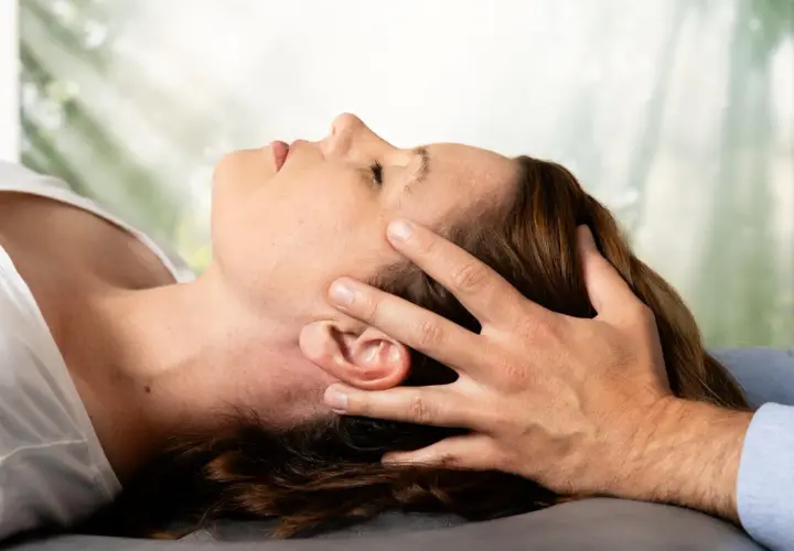 Osteopathie-Behandlung am Kopf, die den Nervus vagus stimuliert. Sanfte Berührung zur Entspannung.