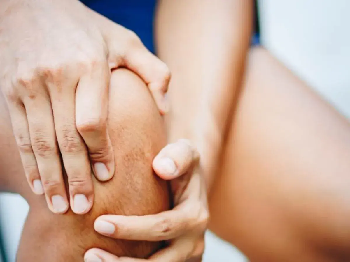 Hände umfassen ein Knie, das auf Schmerzen im Bereich des pes anserinus superficialis und profundus hindeutet.