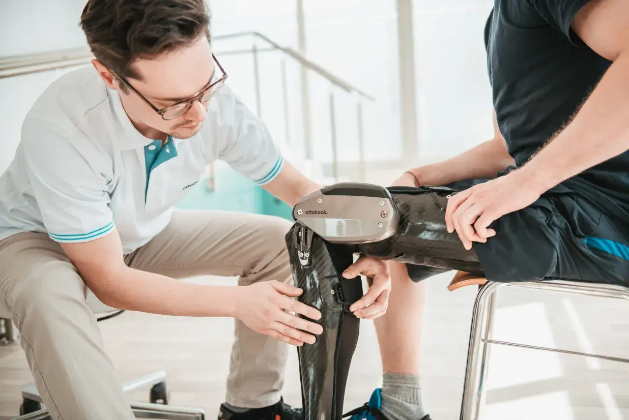 Ein Orthopädietechniker passt eine C-Brace Orthese an einem Patienten an.