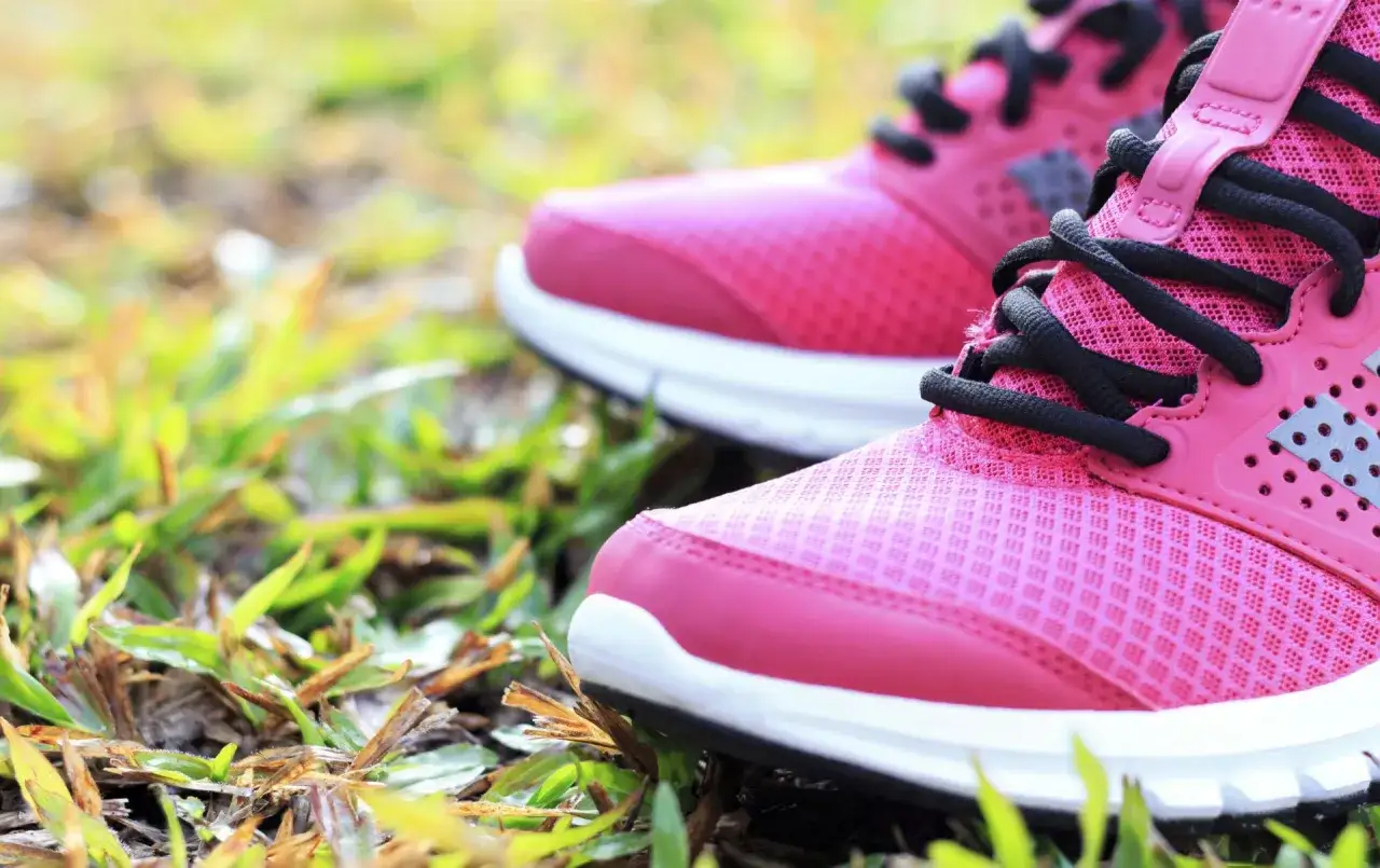 Zwei pinke Laufschuhe mit schwarzen Schnürsenkeln auf grünem Gras. Die richtige Wahl für welche Schuhe bei Kniearthrose?